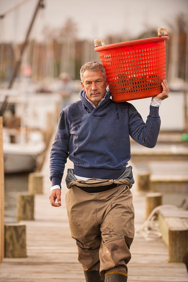 Caucasian fisherman carrying basket on dock