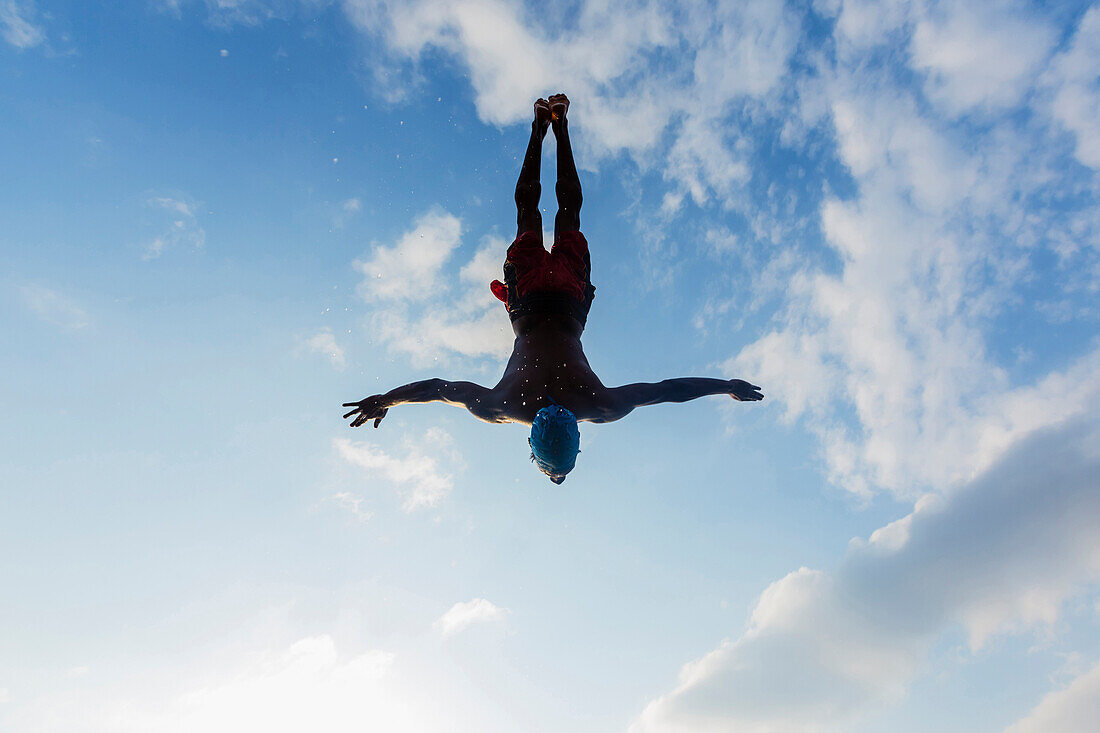Silhouette of man diving against blue sky