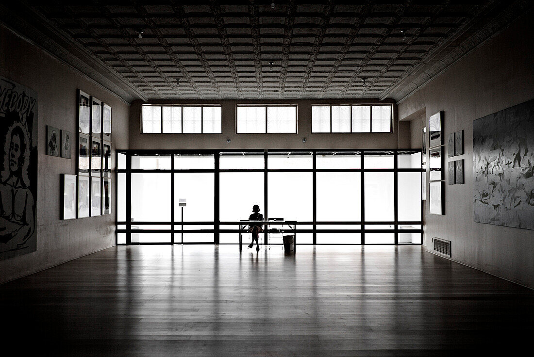 Silhouette of Woman Sitting at Desk in Art Gallery