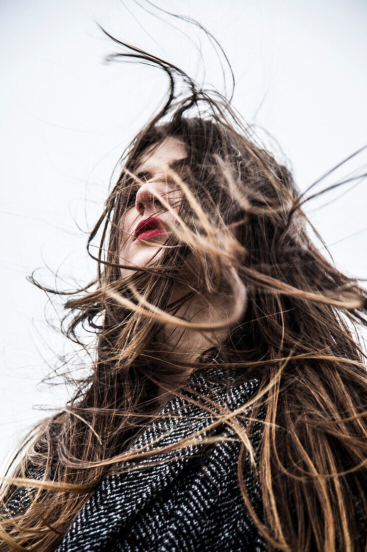 Young Woman with Wind Blowing Hair in Face, Low Angle View