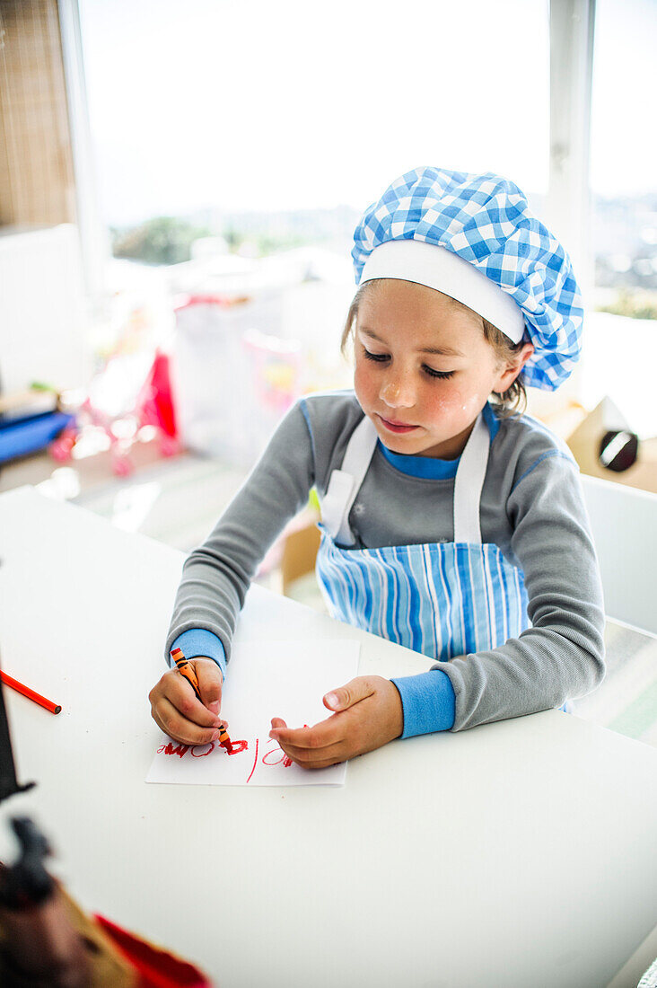 Boy in Chef Hat and Apron Writing Note with Crayon
