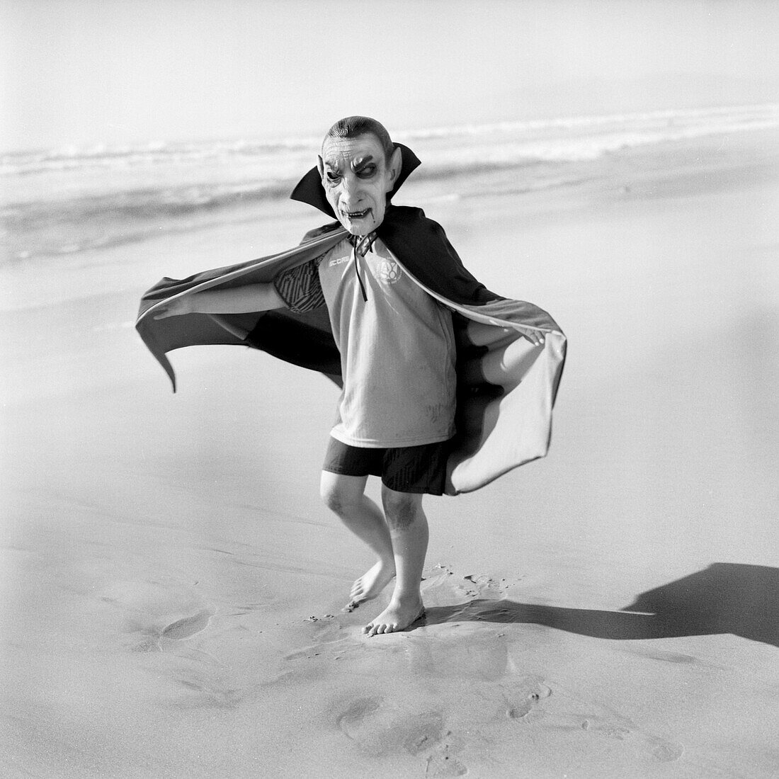 Boy Wearing Scary Dracula Mask and Cape on Beach