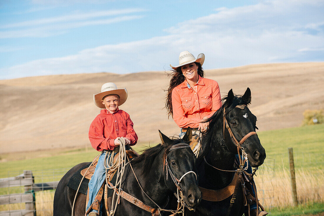 Caucasian mother and son on horseback on grassy hill, Jospeh, Oregon, USA