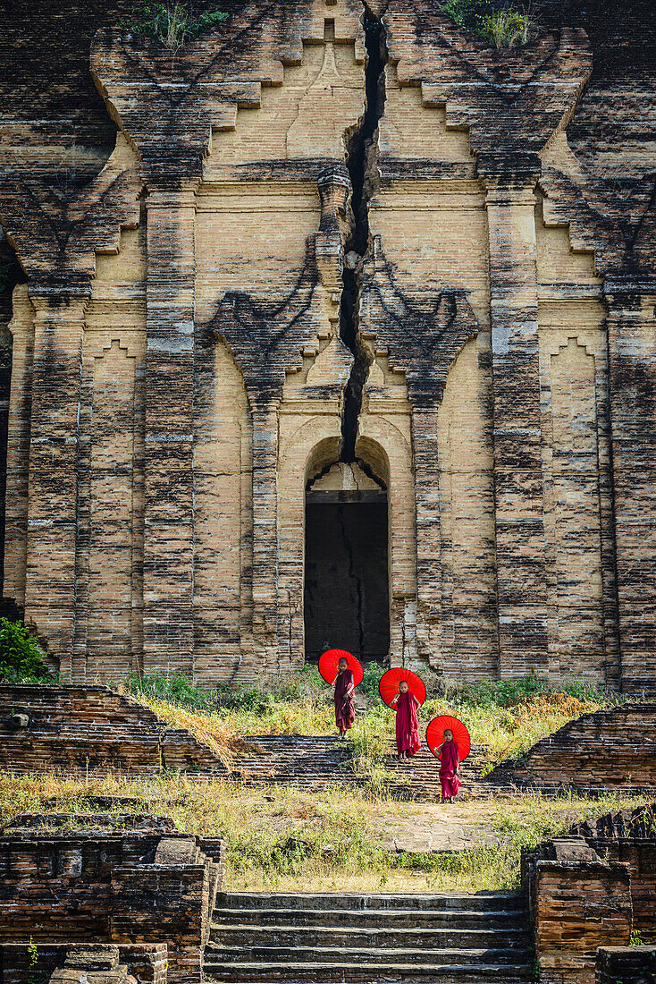 Asian monks standing under umbrellas near historic temple, Mingun, Mandala, Myanmar, Mingun, Mandalay, Myanmar