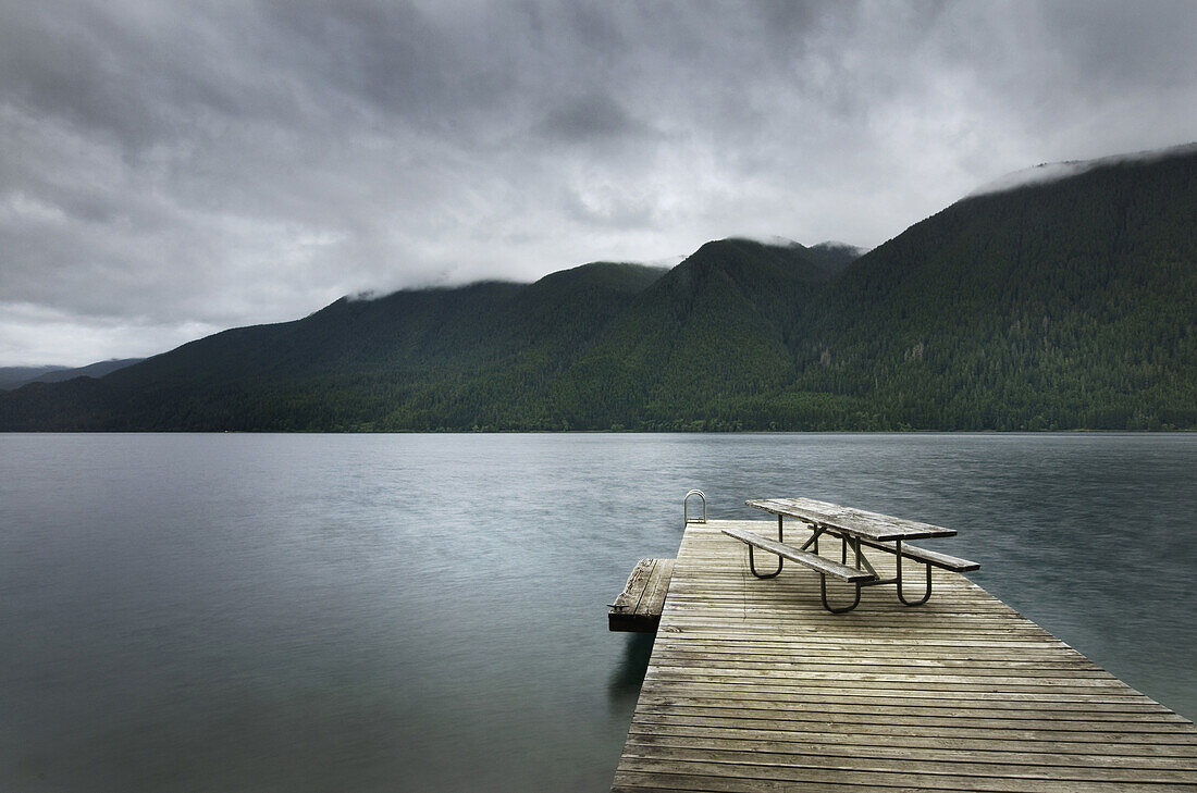 Picnic table on wooden pier at still remote lake, Olympic National Park, Washington, USA