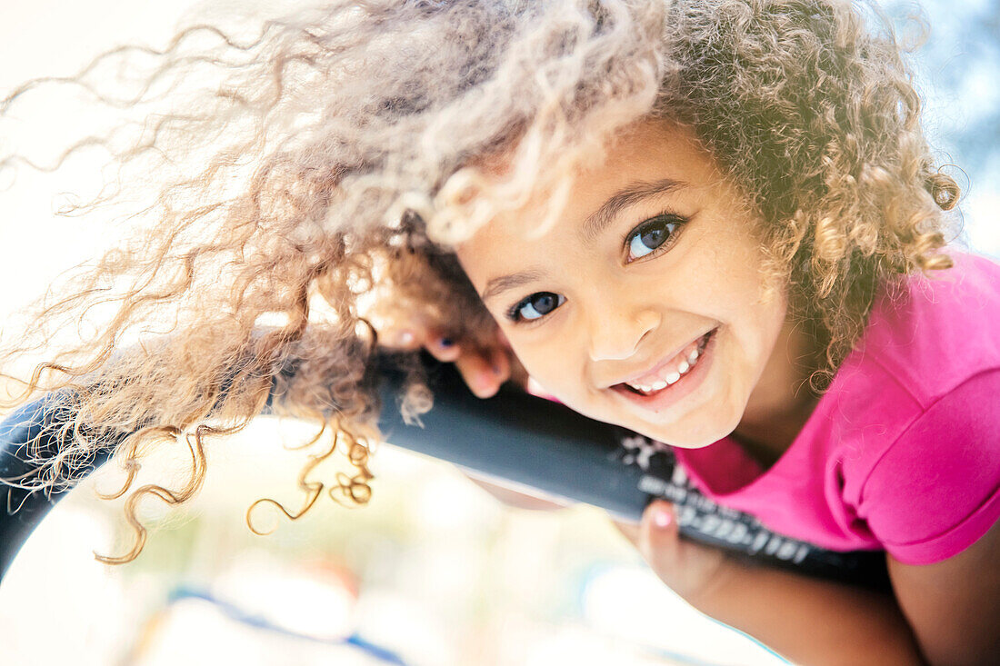 Mixed race girl playing on bicycle rack, C1