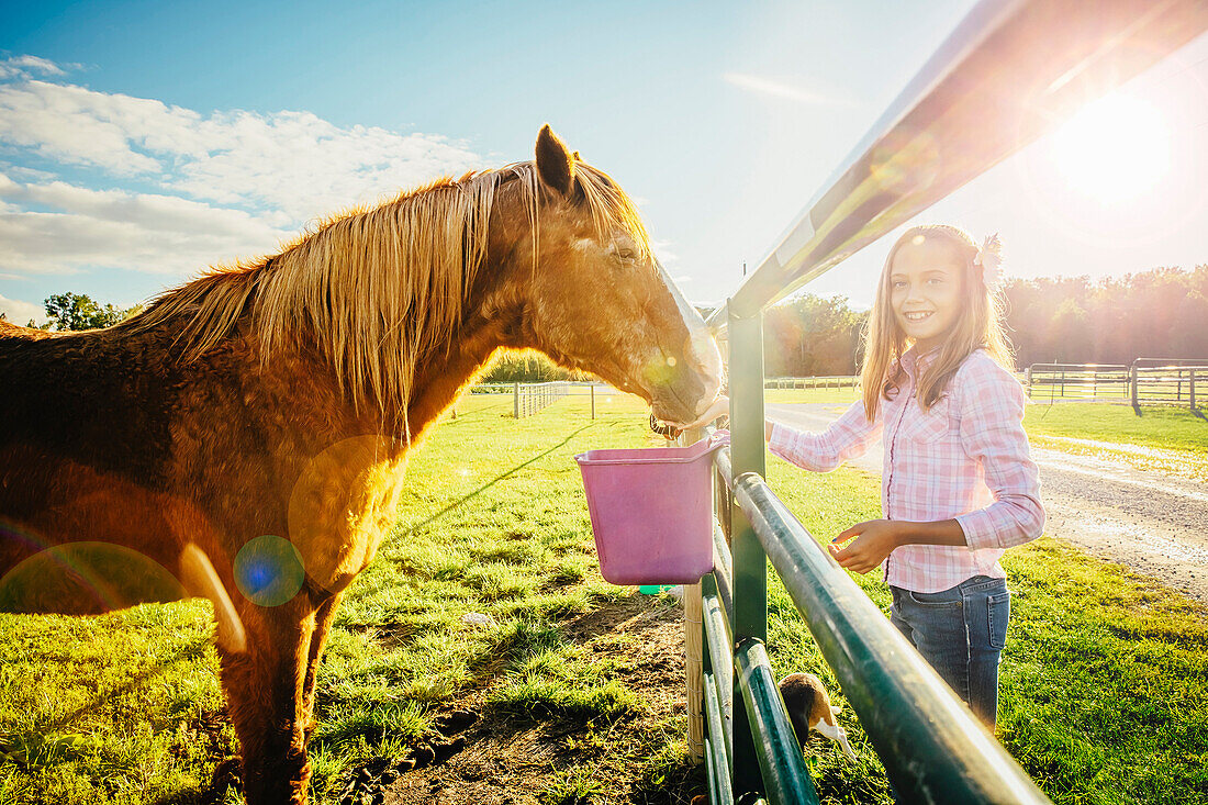 Caucasian girl feeding horse on ranch, C1