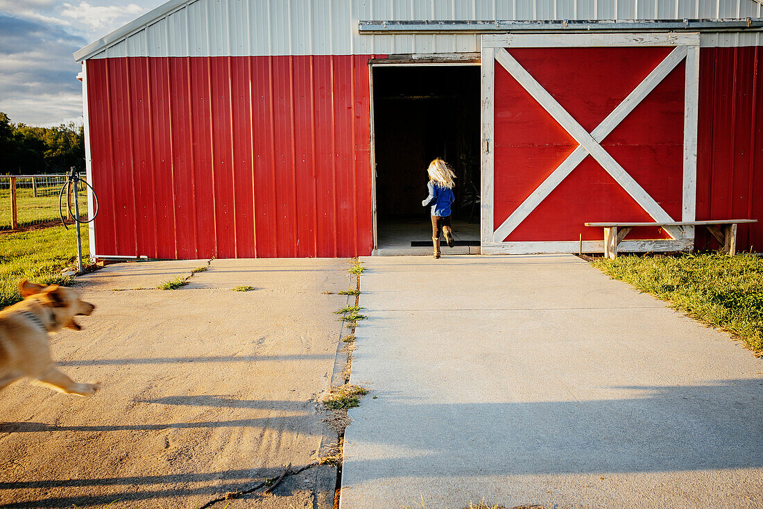 Caucasian girl running to barn on farm, C1