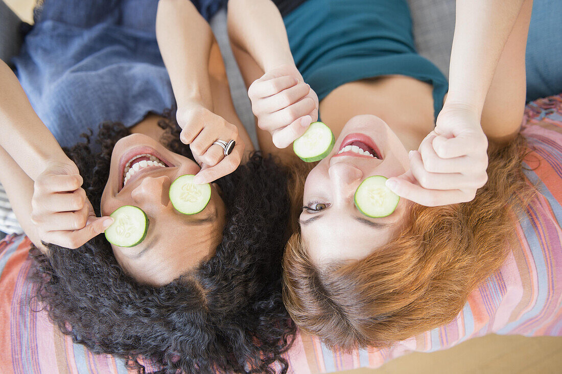 Women holding cucumber slices over eyes, C1