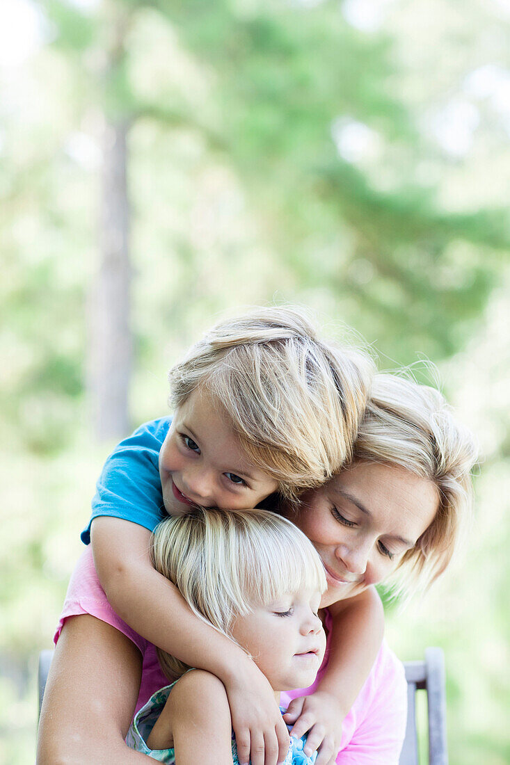 Caucasian mother hugging children outdoors, C1
