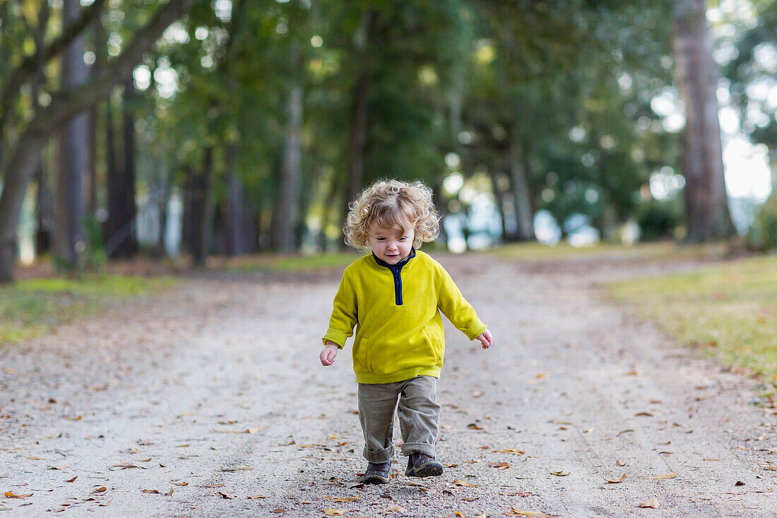 Caucasian baby boy walking on dirt road, C1