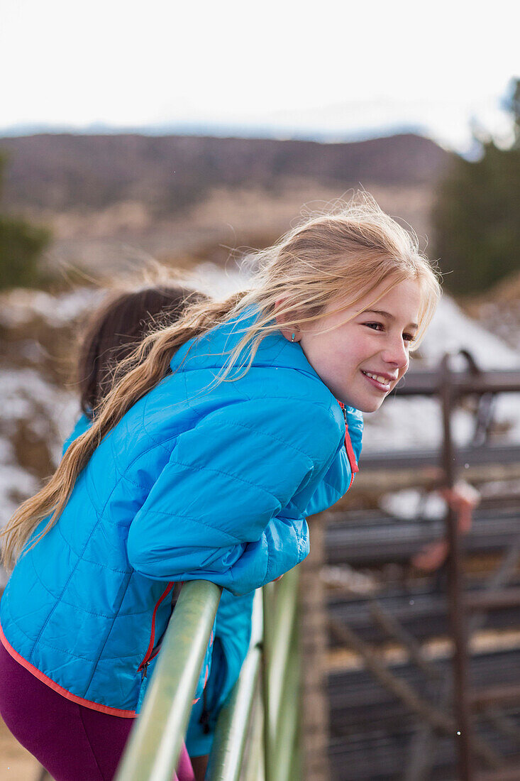 Caucasian girl standing on fence on farm, C1