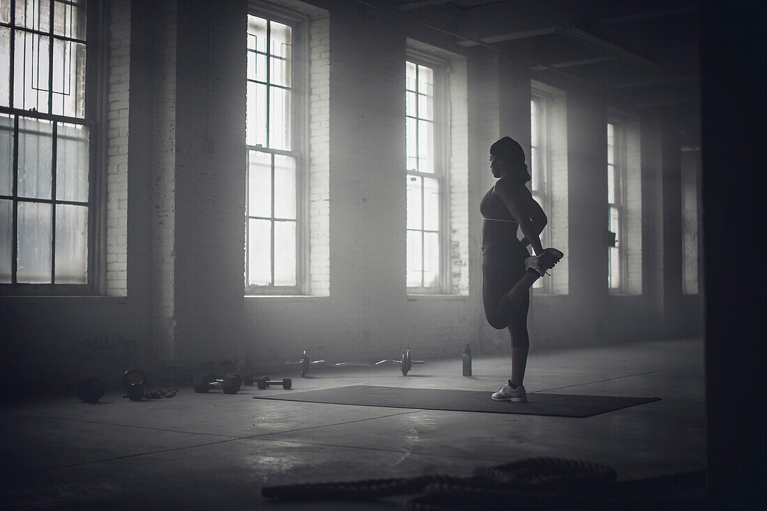 Schwarze Frau dehnt sich in einem dunklen Fitnessstudio, Saint Louis, MO, USA