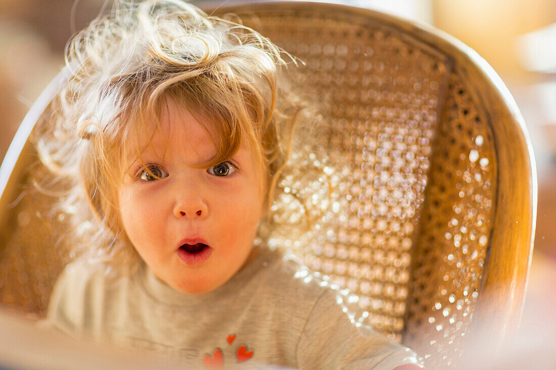 Caucasian baby boy gasping in wicker chair, Santa Fe, New Mexico, USA