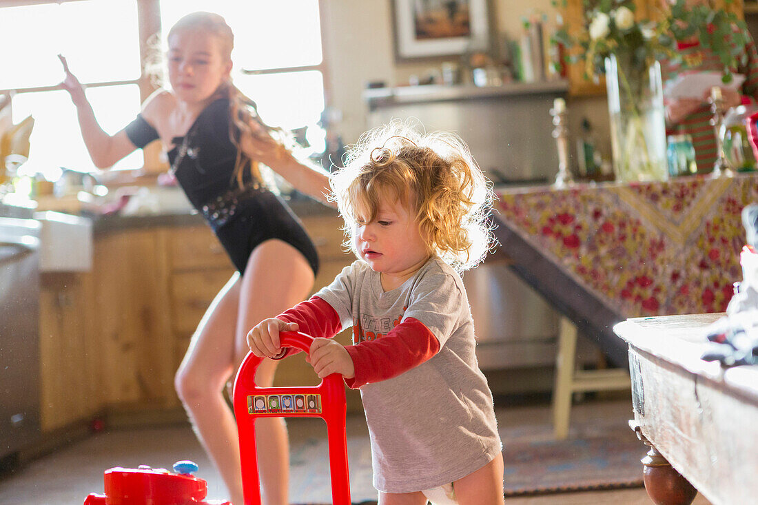 Caucasian baby boy and older sister playing in kitchen, Santa Fe, New Mexico, USA