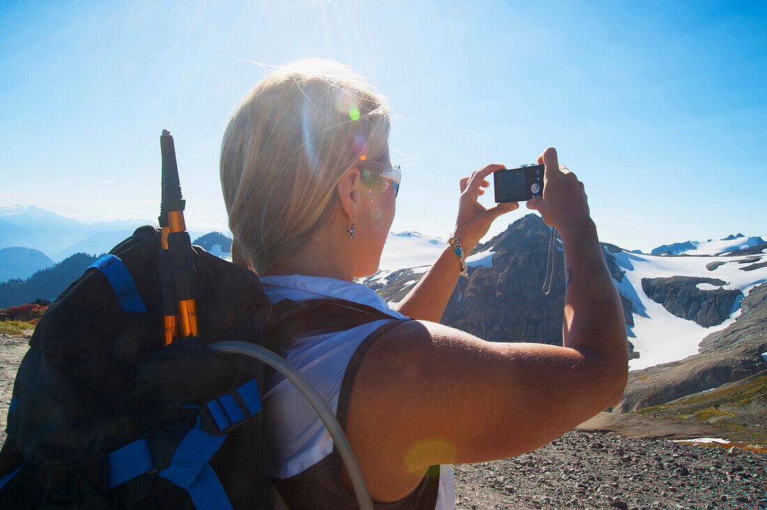 Woman taking photograph of remote mountains, Glacier, Washington, United States