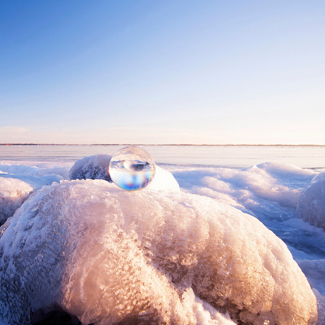 Glass sphere on frozen rock formations, kingston, ontario, canada