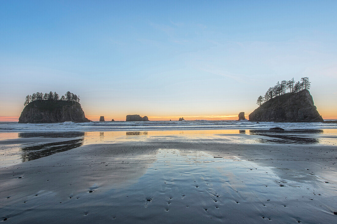 Sunrise horizon behind rock formations on beach, rural, Washington, USA