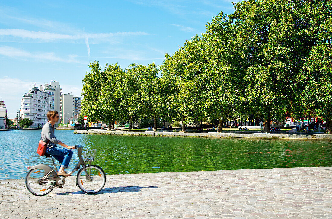 France, Paris, Parc de la Villette, Canal de l Ourcq, man riding a bike