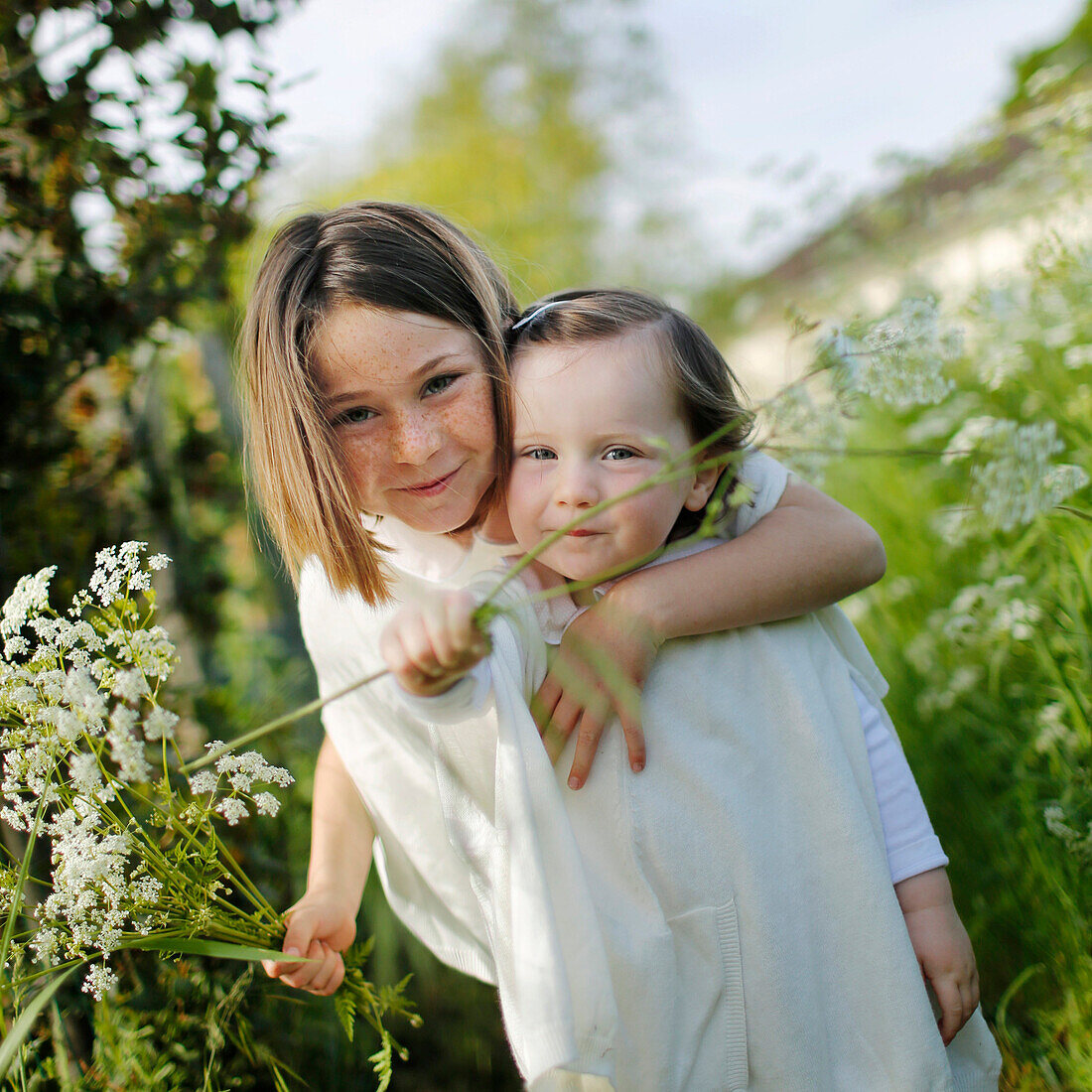 2 young girls in the country holding white flowers