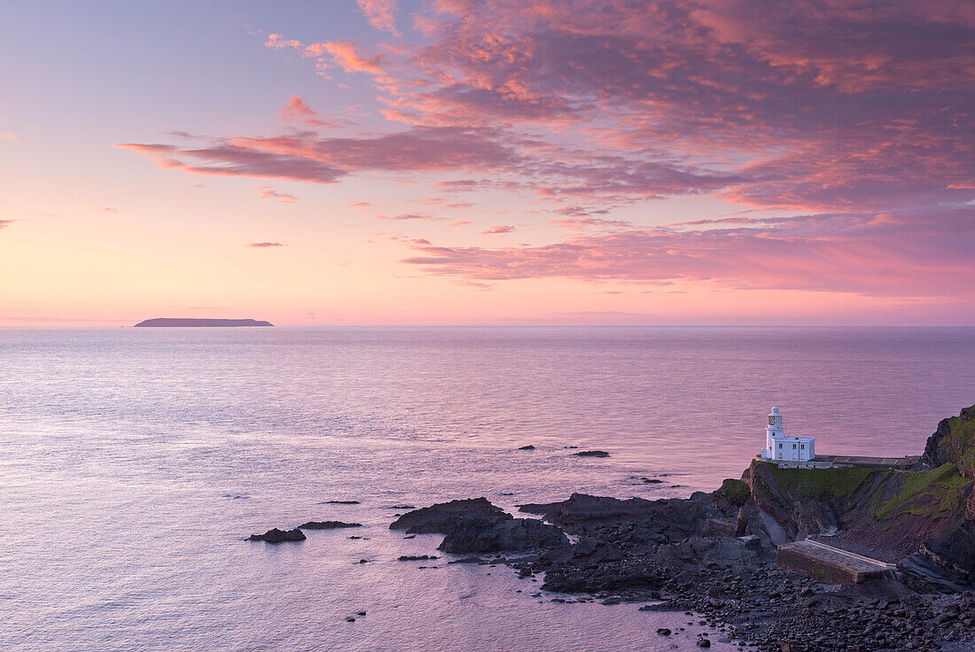 Hartland Point Lighthouse and Lundy Island beneath a colourful sunset, North Devon, England, United Kingdom, Europe