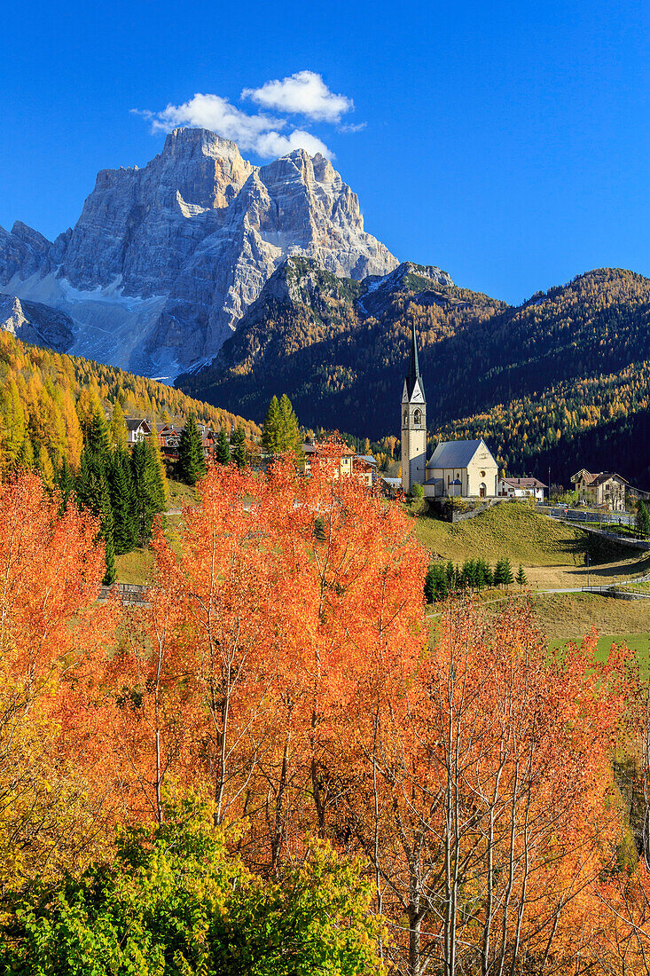 Red and orange trees in front of the tiny church of Selva di Cadore, in the Dolomites, with Mount Pelmo in the background, Veneto, Italy, Europe