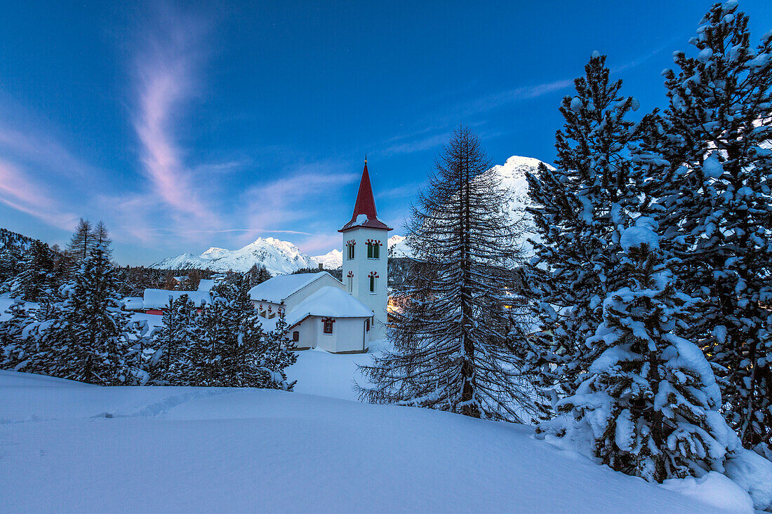 The white church of Maloja Pass in the winter fairy-tale landscape of the Engadine Valley at the blue hour, Graubunden, Switzerland, Europe