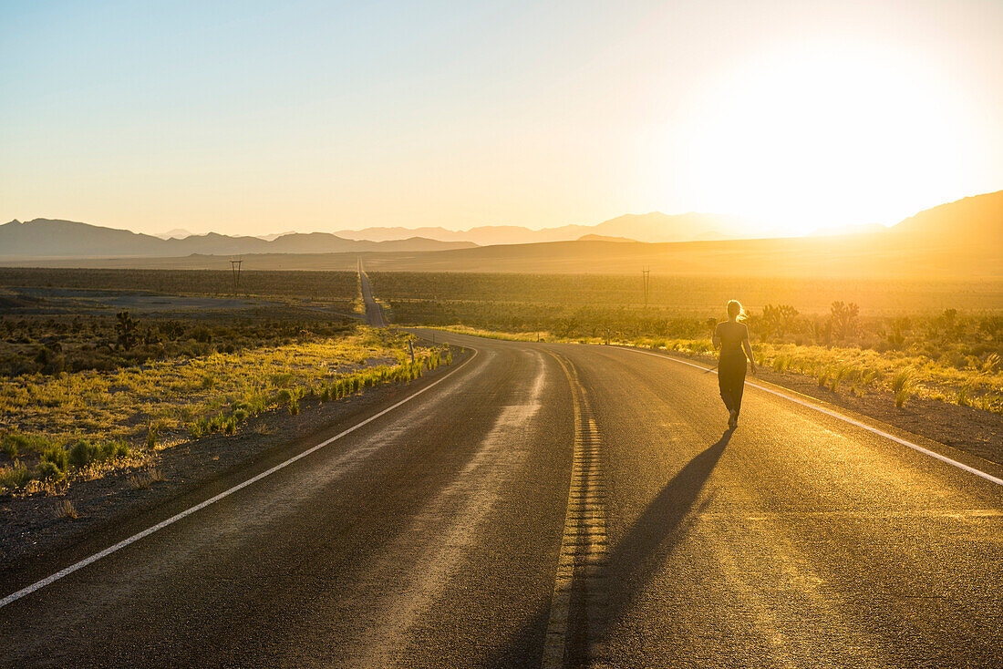 Woman walking down a long winding road at sunset in eastern Nevada, United States of America, North America