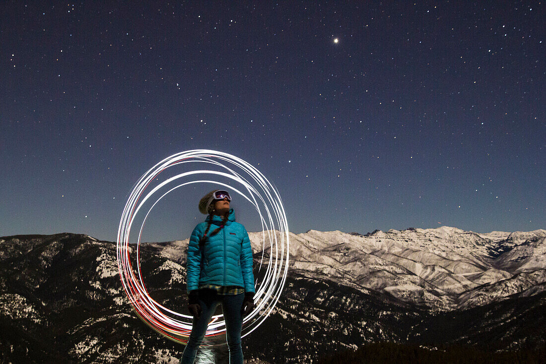 A woman skier looks up into the starry night sky in Montana's backcountry.
