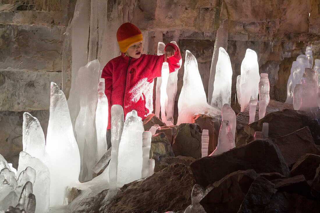 A girl exploring ice stalagmites in a limestone cave in Cascade Creek, San Juan National Forest, Durango, Colorado.