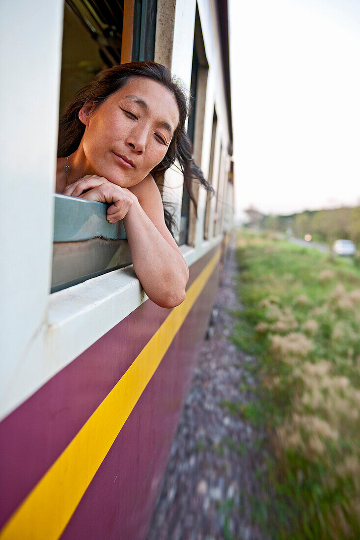 woman leaning out of train window in Chiang Mai in northern Thailand