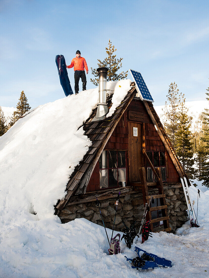 Man prepares to another sled run off the roof of the Peter Grubb ski hut, Sierra Nevada