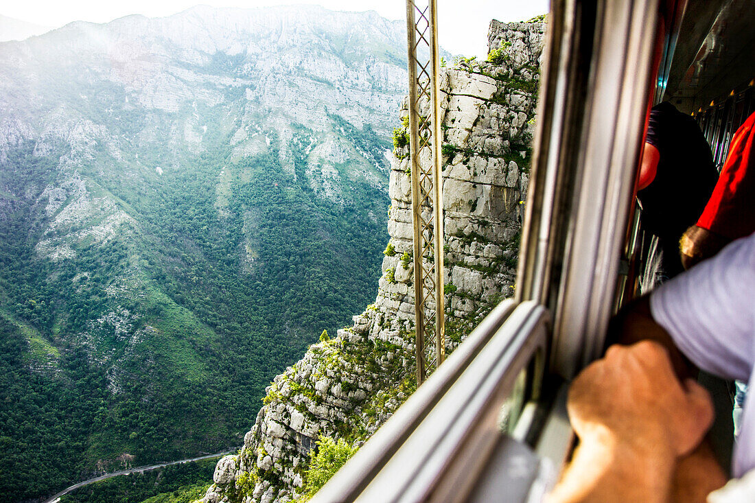 A man looking through the window of a moving train at the  Moraca canyon, Montenegro.
