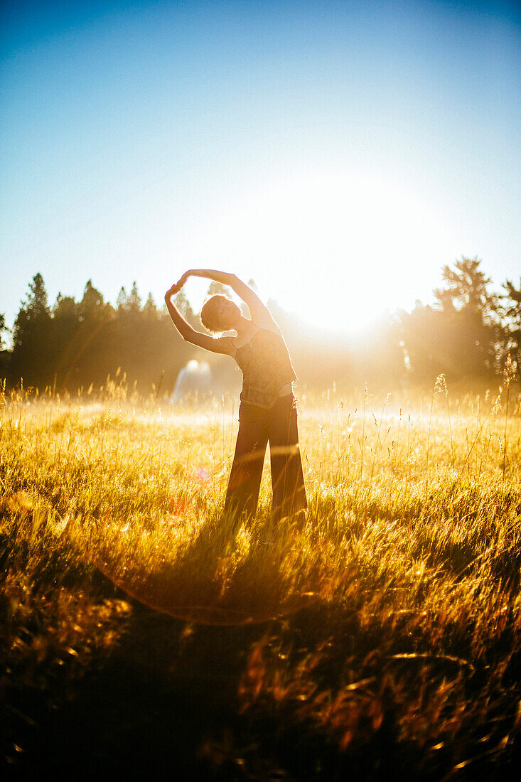 A woman doing yoga in the early morning light.