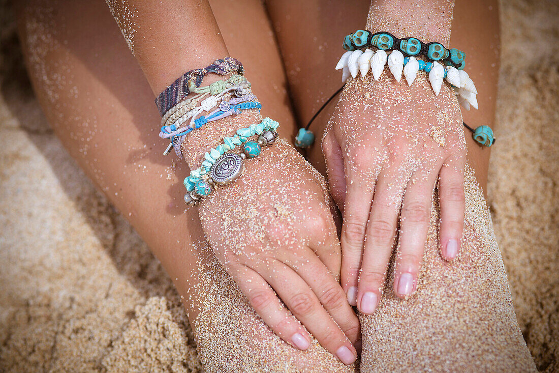 Female hand with bracelets on the beach.