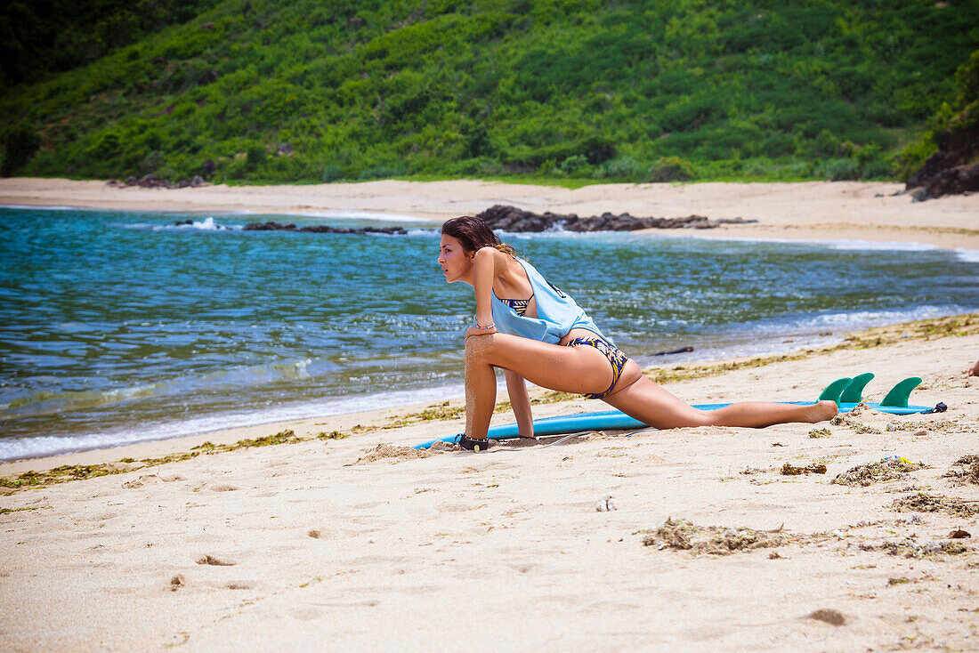 Young girl stretching on the beach before surfing,Lombok,Indonesia.