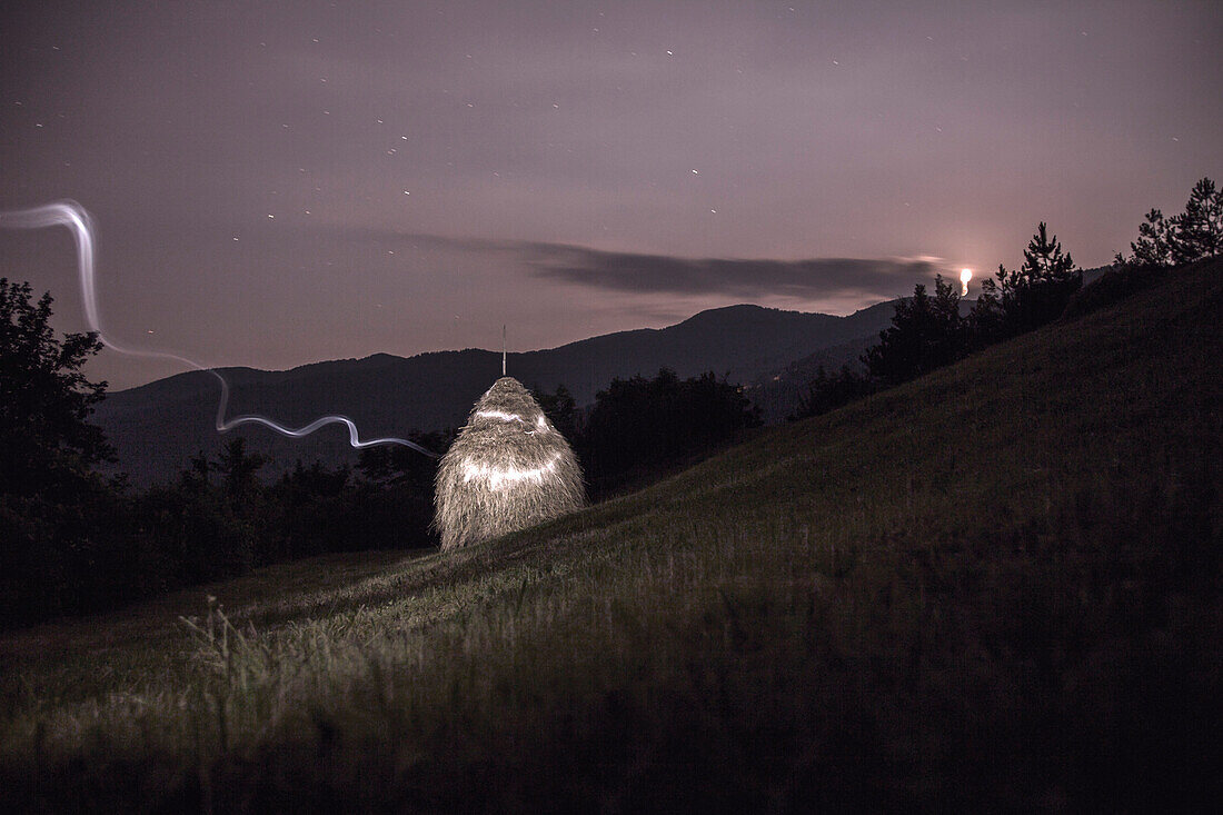 Painting with light on a haystack. Hay is on a slope with mountain Radocelo in the background.