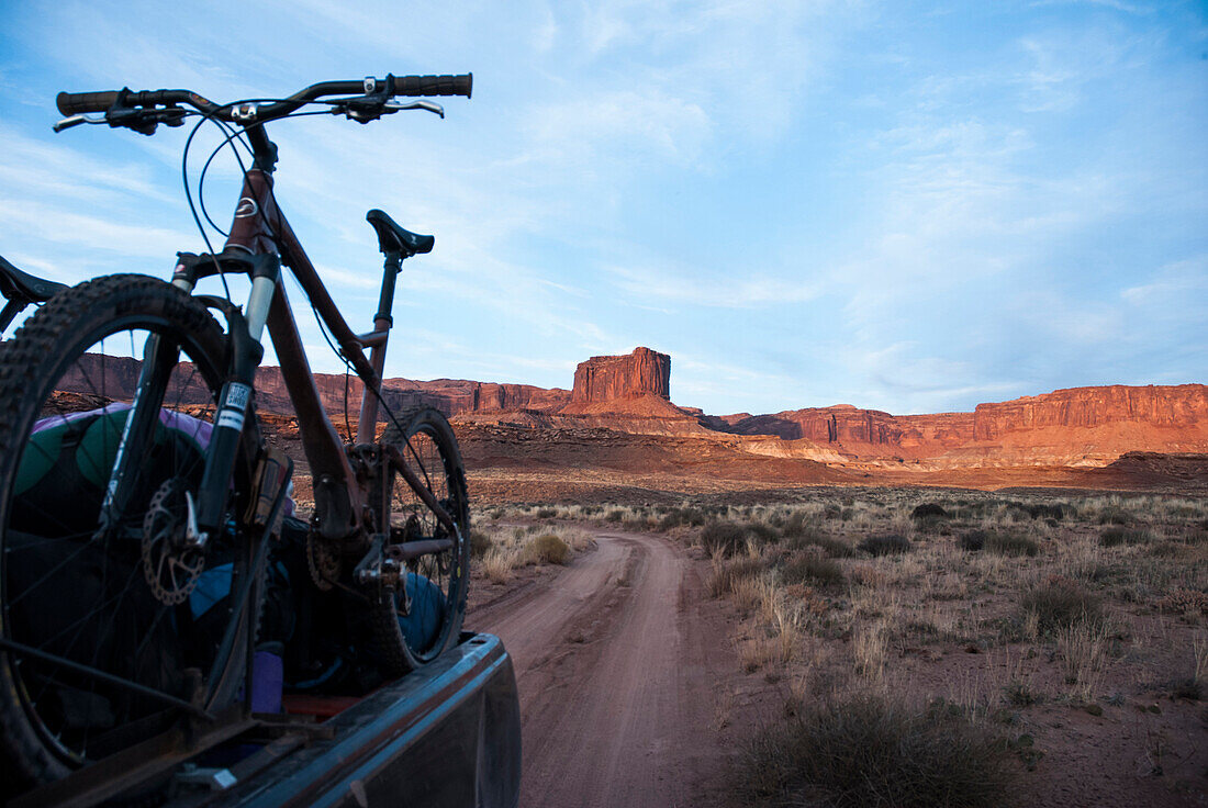 Riders shuttle bikes and gear through the canyon as the sun sets during a tour of the White Rim Trail near Moab, Utah.