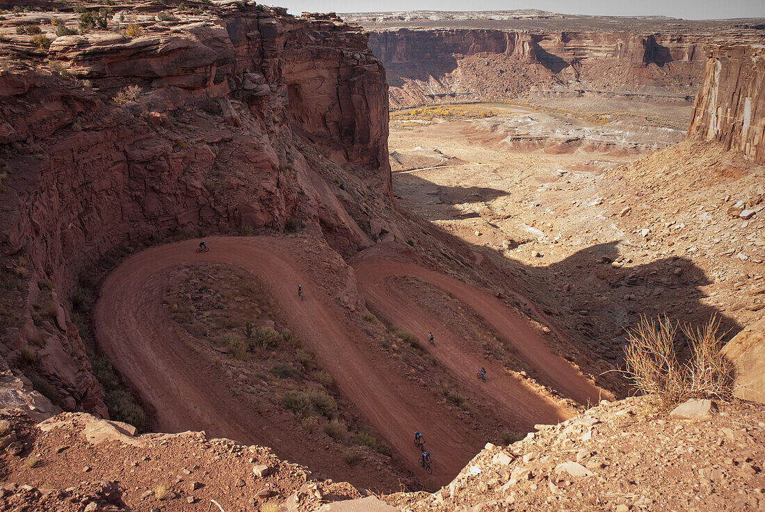Riders decend into the canyon on  mountain bikes while touring the White Rim Trail near Moab, Utah.