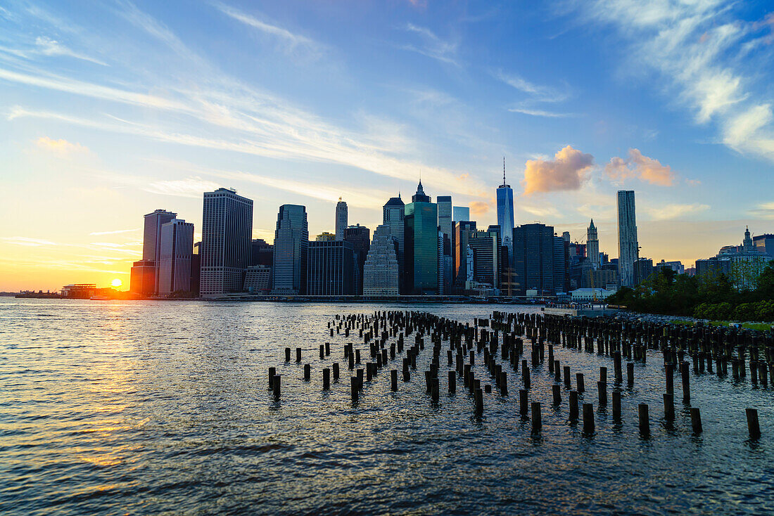 Lower Manhattan skyline at sunset, the remains of old warehouse pilings in the foreground, New York, United States of America, North America