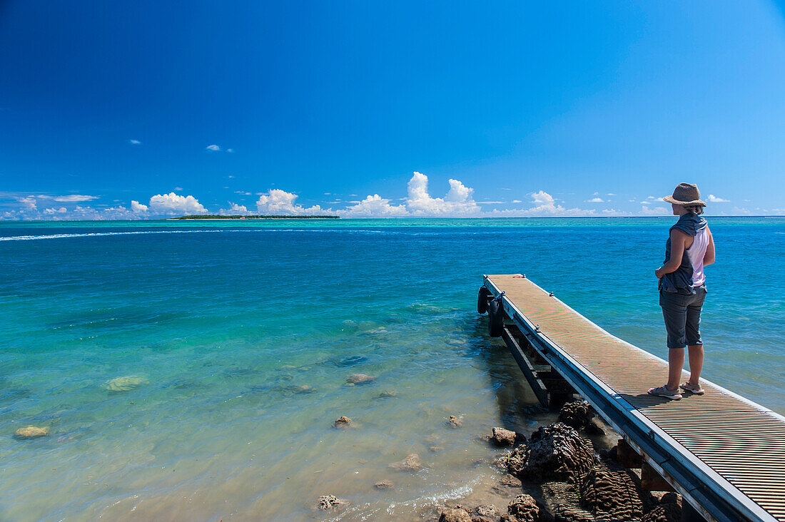 Tourist standing on a little pier with Cocos Island in the distance, Guam, US Territory, Central Pacific, Pacific