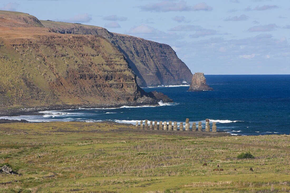 Elevated view of a row of monolithic stone Moai statues at Tongariki and the rugged coastline of Rapa Nui (Easter Island), UNESCO World Heritage Site, Chile, South America
