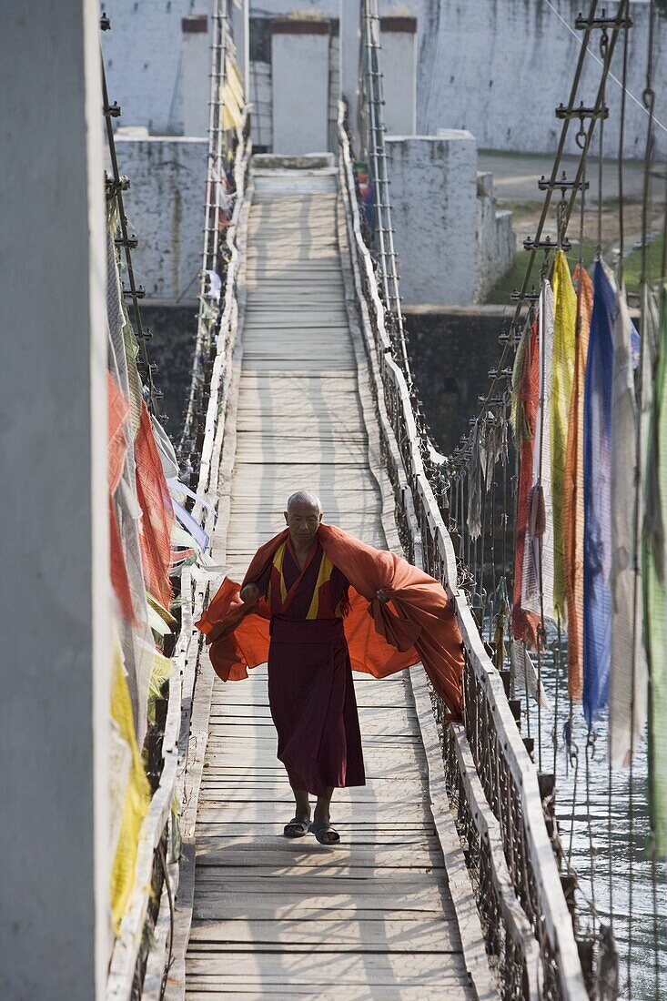 Buddhist Monk crossing bridge to Punakha Dzong, Punakha, Bhutan, Asia