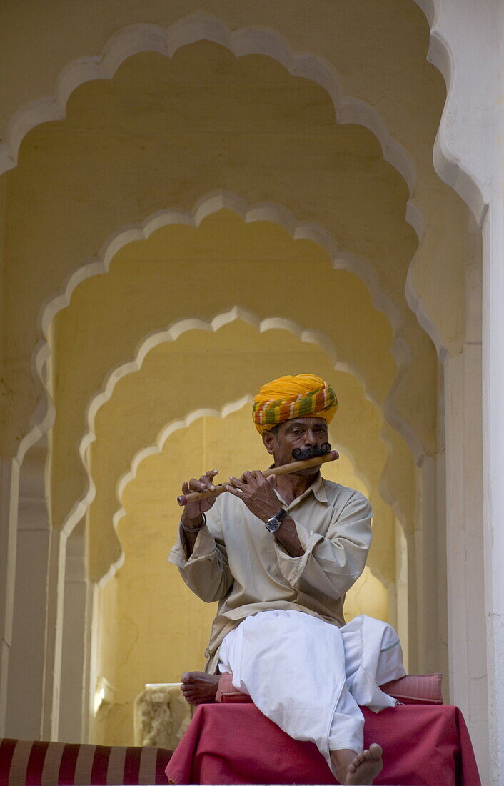 A man in traditional Indian dress playing a wooden flute at the Meherangarh Fort in Jodhpur, Rajasthan, India, Asia