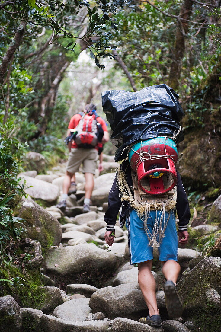 Porter and hiker on trail, Kinabalu National Park, Sabah, Borneo, Malaysia, Southeast Asia, Asia