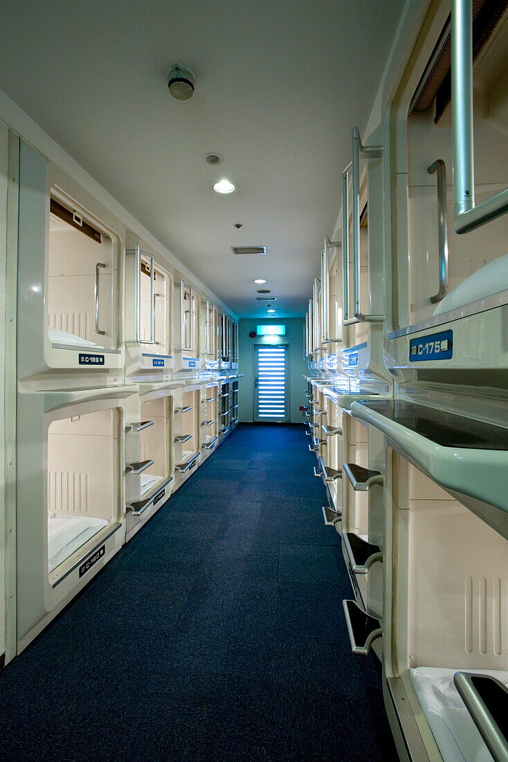 Rows and stacks of sleeping compartments along one corridor at a capsule hotel in Osaka, Japan, Asia