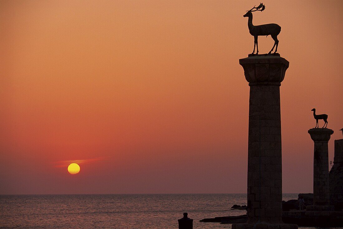 Buck statues at the entrance to Mandraki Harbour, silhouetted at dawn, Rhodes, Dodecanese Islands, Greek Islands, Greece, Europe