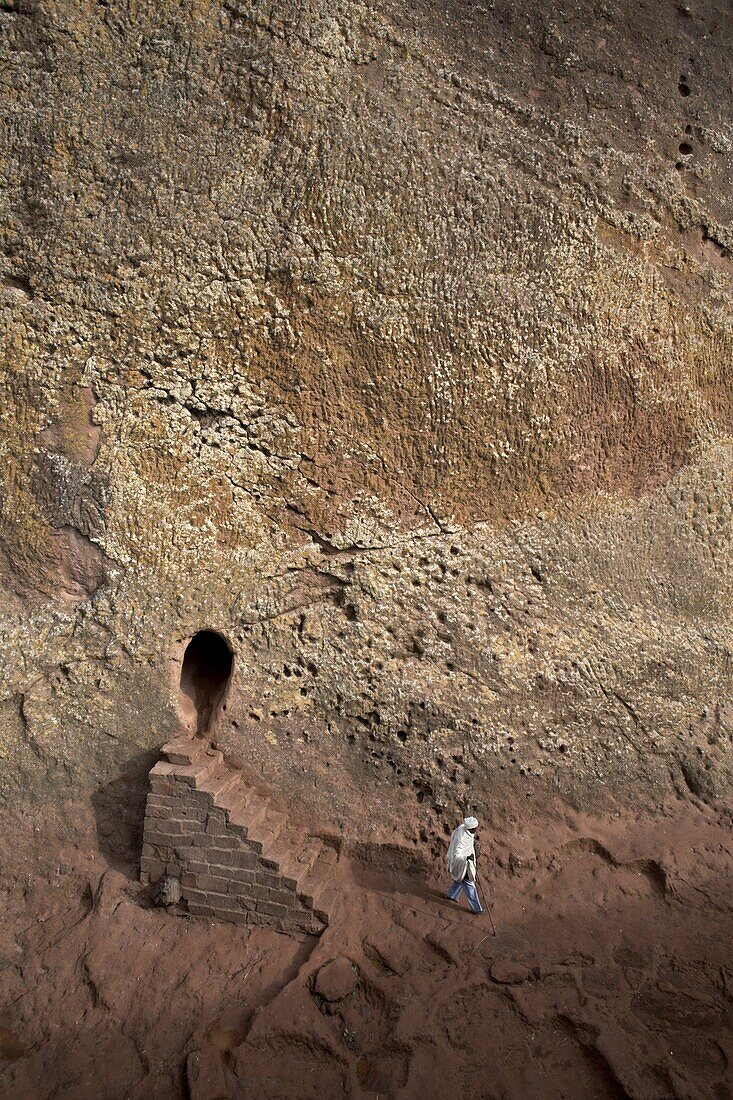 A woman emerges from a tunnel leading to the rock-hewn church of Bet Amanuel, in Lalibela, Ethiopia, Africa