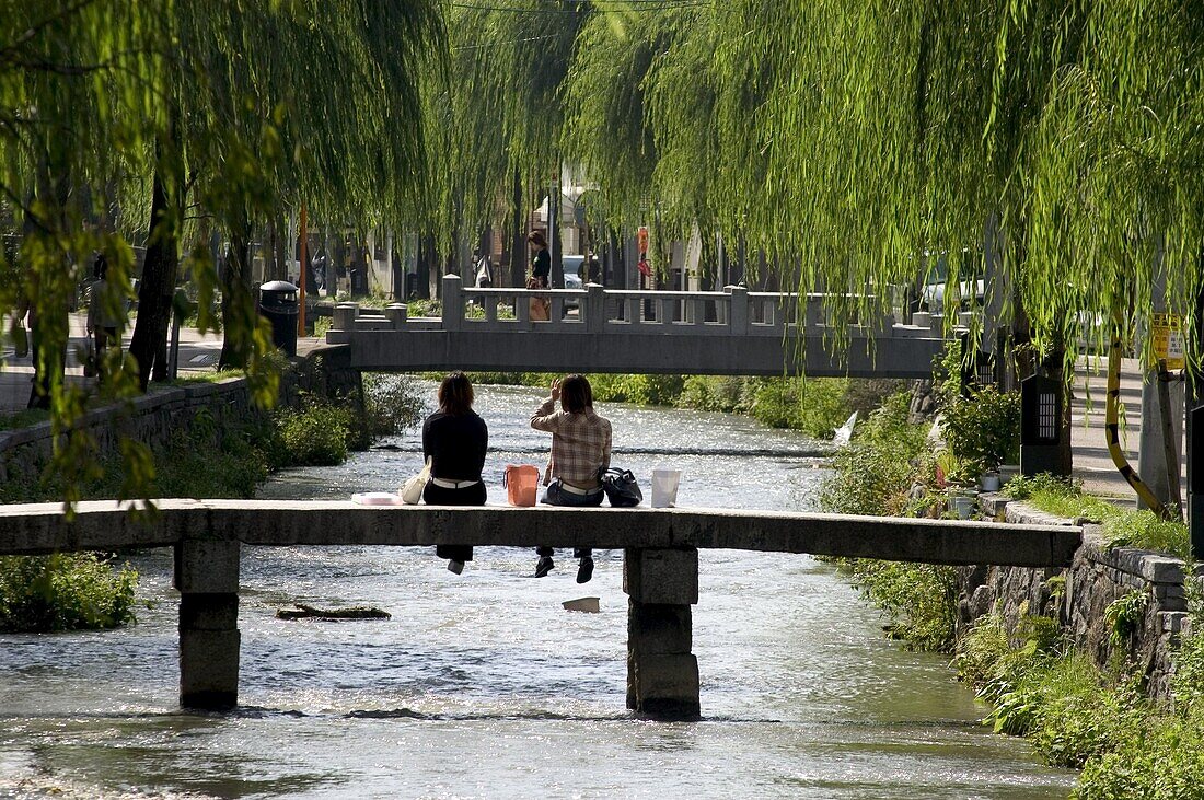 Two girls sitting on bridge, Kyoto city, Honshu, Japan, Asia