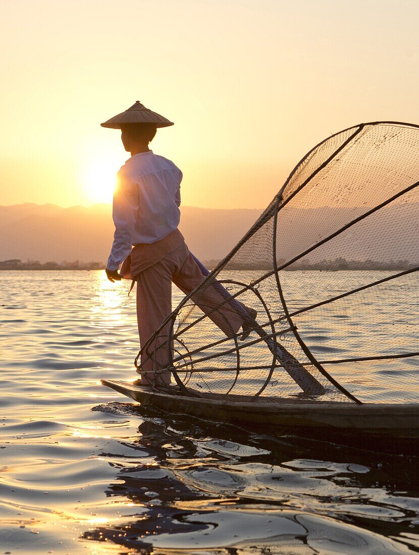 Intha 'leg rowing' fishermen sunset on Inle Lake who row traditional wooden boats using their leg and fish using nets stretched over conical bamboo frames, Inle Lake, Myanmar (Burma), Southeast Asia